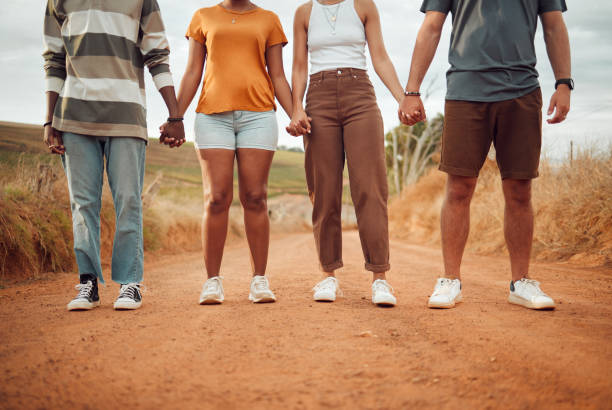 istock Legs, diversity and people holding hands together in solidarity, connection or support. Trust, friendship help and outdoor desert group, team or friends walk, travel or stand in countryside dirt road 1445984736