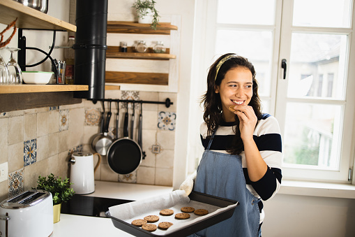 Portrait of a beautiful, young woman baking cookies at her kitchen