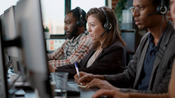istock Young woman using audio headset and computer at call center 1445989772