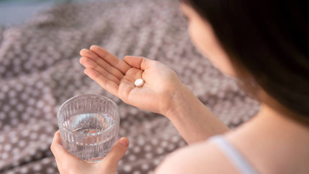 donna che tiene la pillola in mano con l'acqua. concetto di salute - painkiller pill capsule birth control pill foto e immagini stock