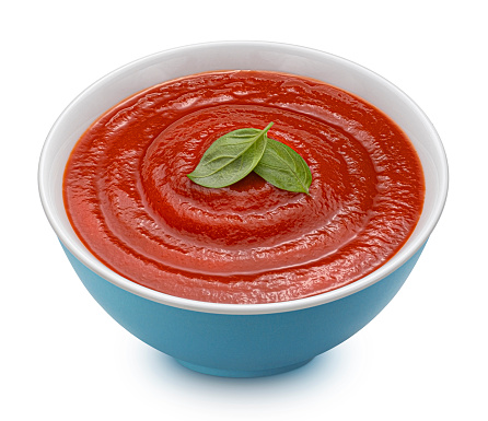 Bowl of tomato paste with basil leaf isolated on white background with clipping path. Full depth of field