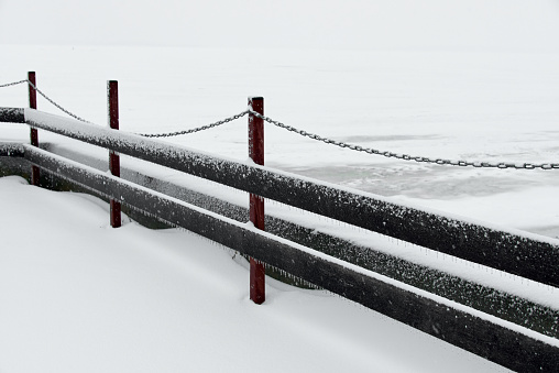 Beautiful winter landscape of Wooden fence with chain on the snow-covered ice of the river. Clean winter season concept.