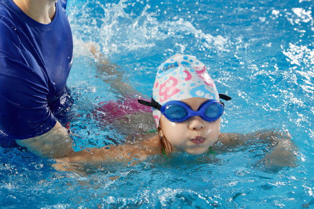 Little child learning to swim in pool with teacher