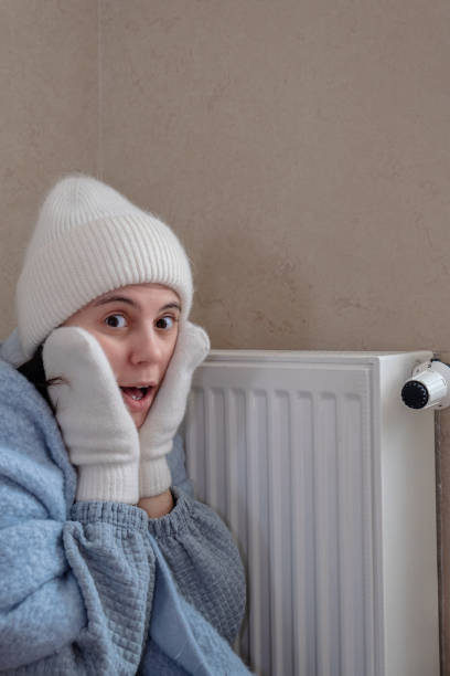 Despite the fact that the woman is dressed warmly, she is shocked to find that the heat is not working stock photo