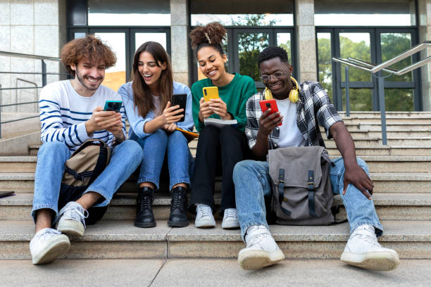 istock Multiracial college student friends look mobile phone laughing together. University students using smartphone outdoors. 1445997727