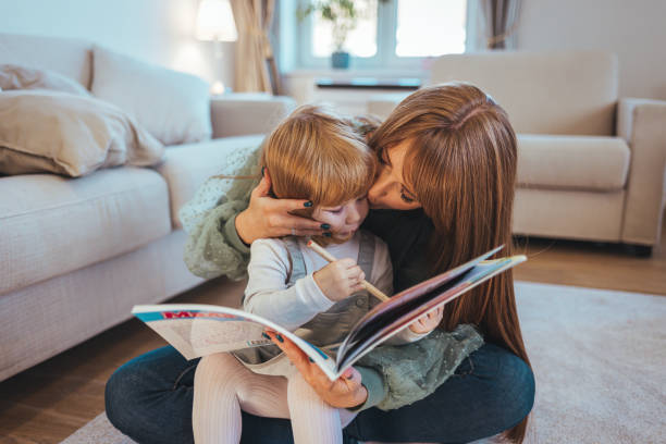 istock Mother reading a book to her daughter on carpet 1445998743