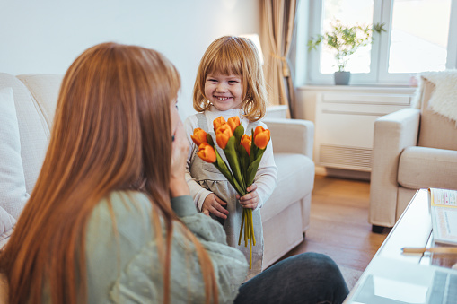 Trendy attractive cheerful mother and daughter enjoying holiday together having big flawless seasonal colorful bouquet of tulips, comfort pleasure joy enjoyment concept on grey background