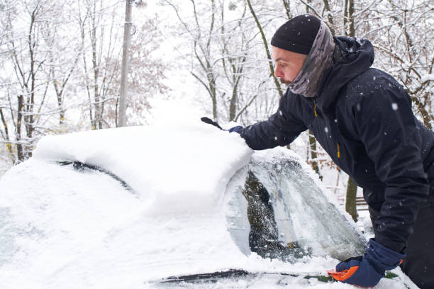 istock Man cleans his car after a snowfall. Cleaning snow from windshield, Scraping ice, Winter car window cleaning 1445999162