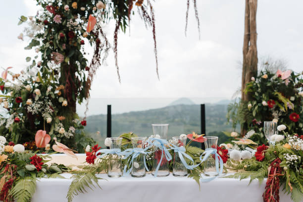 istock Beautiful rustic theme outdoor wedding white altar setup, wedding sand ceremony vases pouring glass lined up with natural flower decoration and mountain background. 1446000201