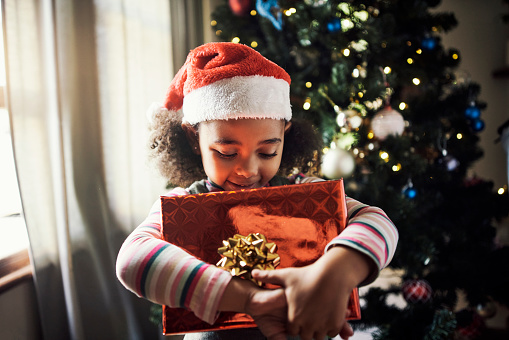 Child, christmas and gift while excited and celebrating the festive season with joy. Xmas, present box and little girl holding a package to be opened in a family home