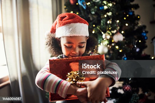 istock Child, christmas and gift while excited and celebrating the festive season with joy. Xmas, present box and little girl holding a package to be opened in a family home 1446004087
