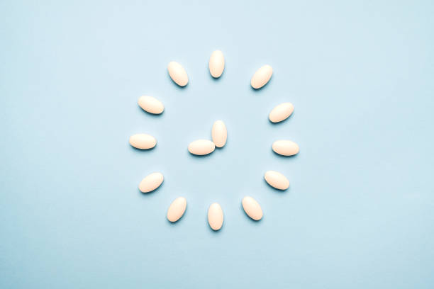 time to take pills. clock created from white pills on  blue background. right time for using medicines - narcotic medicine pill insomnia imagens e fotografias de stock