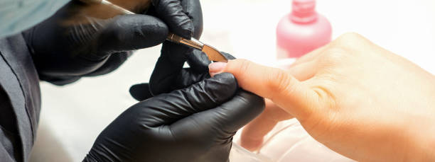 istock Close up professional manicurist master holding customer hand while using a cuticle pusher in a nail salon. 1446014724