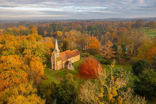 Aerial photo from a drone of All Saints Church in Great Braxted, Essex, UK surrounded by autumnal coloured trees. Historic records go back to the time of Edward the Confessor (1042) and the church have registers going back to 1558. This photo was captured on the 1st December 2022.