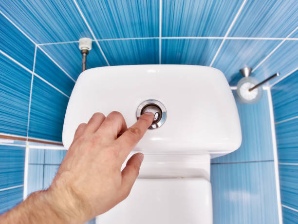 homem pressiona o botão do vaso sanitário com a mão e drena a água no banheiro. visão em primeira pessoa. espaço interior de casa de banho para homens. - flushing - fotografias e filmes do acervo
