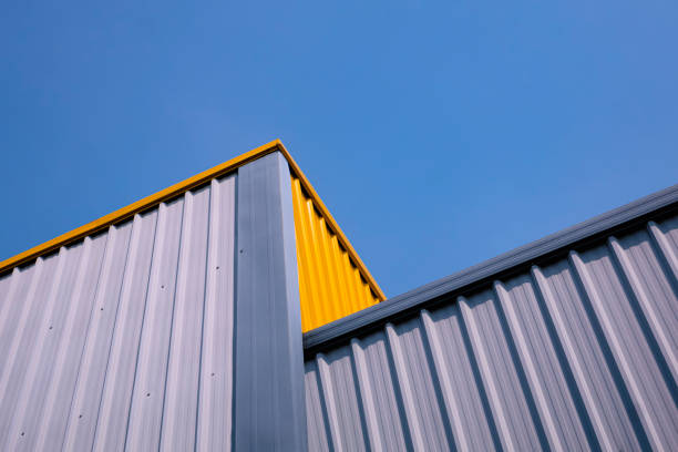 unteransicht der grauen und gelben wellblechwand des modernen lagergebäudes in verschiedenen ebenen vor blauem, klarem himmelshintergrund - architecture roof aluminum sheet industry stock-fotos und bilder