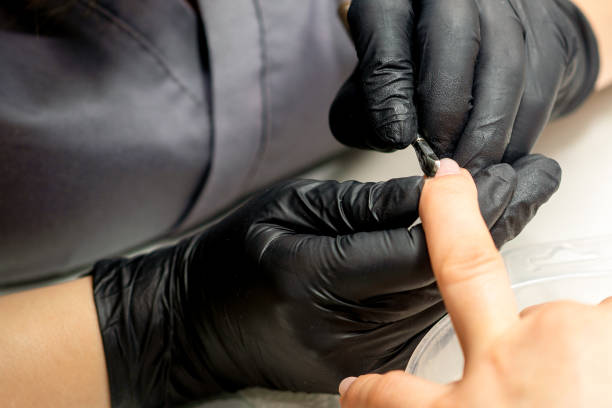 istock Close up professional manicurist master holding customer hand while using a cuticle pusher in a nail salon. 1446029591
