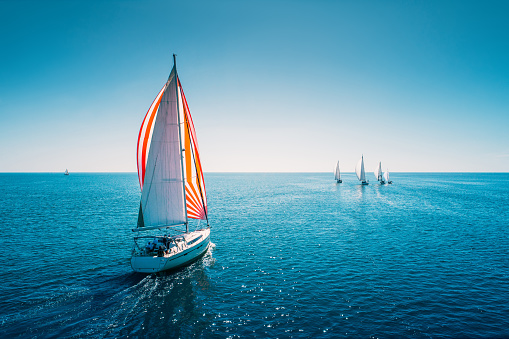 Regatta sailing ship yachts with white sails at opened sea. Aerial view of sailboat in windy condition