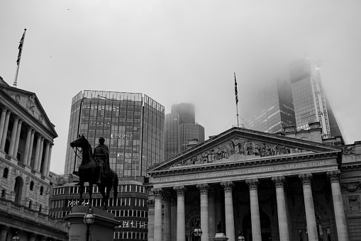 London Financial district on a foggy day in November 2022. The inscription on the statue reads;\nOn 19th July 1838 the Court of Common Council of the City of London agreed to a contribution of £500 toward the cost of the above statue of the Duke of Wellington in appreciation of his efforts in assisting the passage of the London Bridge Approaches Act 1827. This Act led to the creation of King William Street. The government donated the metal, which is bronze from captured enemy cannon melted down after the Battle of Waterloo, and valued at the time at £1500. The total cost of the statue was £9000. The remainder being raised by public subscription.\nThe sculptor, Sir Francis Chantrey (1781 to 1841), was commissioned in 1838 but died before the work was completed. It was finished by his assistant Henry Weekes (1807 to 1877).\nThe Lord Mayor, William Magnay, unveiled the statue on 18th June 1844, the anniversary of Waterloo, in the presence of his guest the King of Saxony.