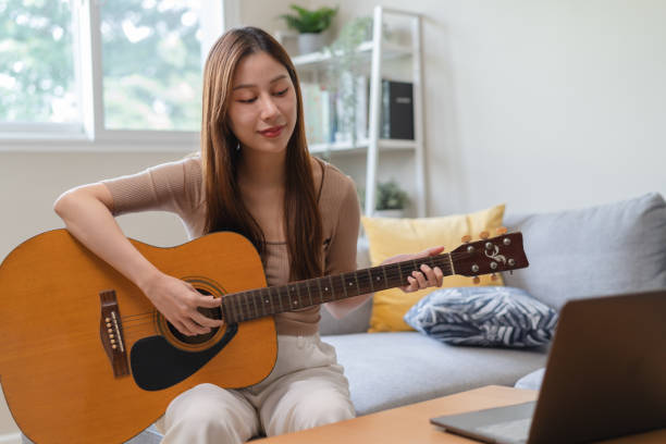 istock Young  woman sitting on the sofa and playing guitar. 1446031329