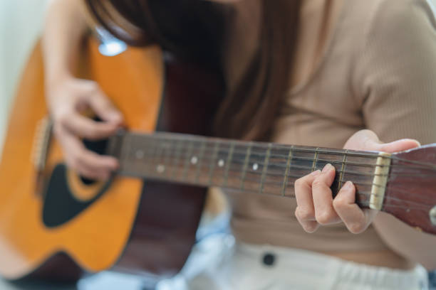 istock Young  woman sitting on the sofa and playing guitar. 1446031338