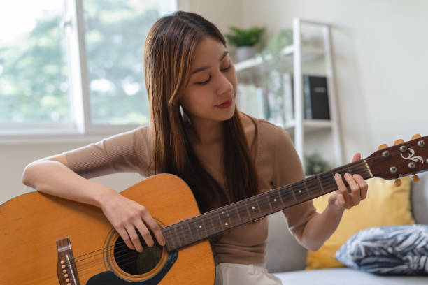 istock Young  woman sitting on the sofa and playing guitar. 1446031339