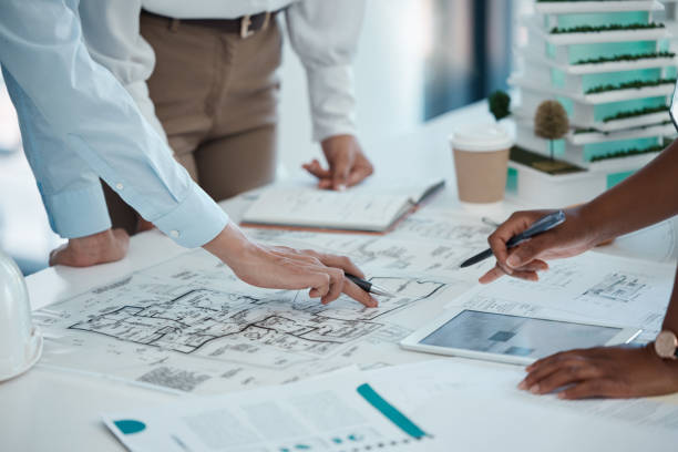 istock Architect, hands and planning building on paper for construction design or layout at the office. Group hand of employee in teamwork project plan for architecture working on model build or blueprint 1446034342