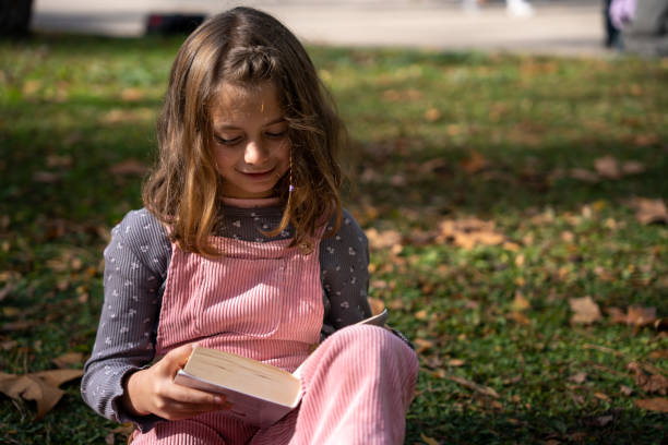 istock Girl reading book in park 1446035226