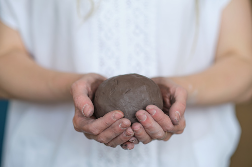 women's hands shake a piece of gray clay. Prepare to work in a pottery workshop. Pottery made of clay with their own hands. Holding a grey ball.