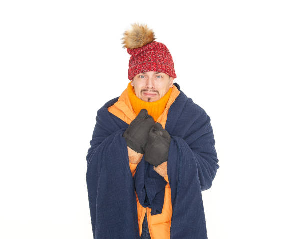Young handsome man wearing in red hat, yellow down jacket and plaid feeling cold on white background. Gas crisis concept