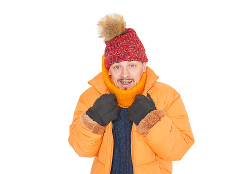 Young handsome man wearing in red hat and yellow down jacket feeling cold on white background. Gas crisis concept