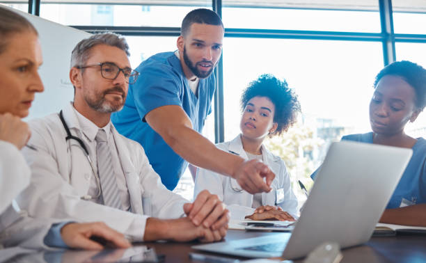 médico, reunião e laptop para equipe em escritório em discussão, brainstorming e planejamento. médico, enfermeiro e computador na mesa mostram diversidade em colaboração, trabalho em equipe ou workshop para análise de dados - ideas education healthcare and medicine indoors - fotografias e filmes do acervo