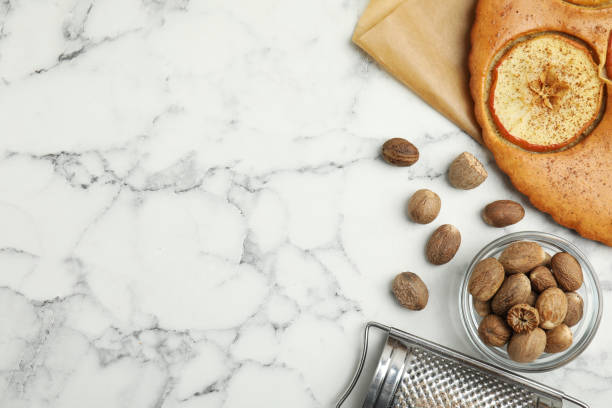 istock Nutmeg seeds, grater and tasty apple pie on white marble table, flat lay. Space for text 1446046655