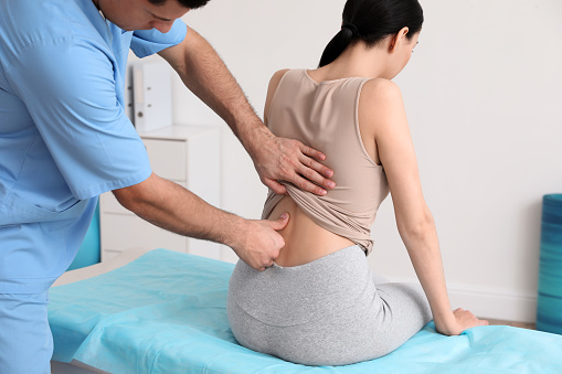 Orthopedist examining woman's back in clinic. Scoliosis treatment