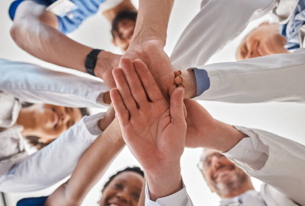 istock Hands, doctor and teamwork below in hospital for motivation, inspiration and diversity at work. Medical, team and hand together in collaboration at clinic, help community in healthcare and wellness 1446048205