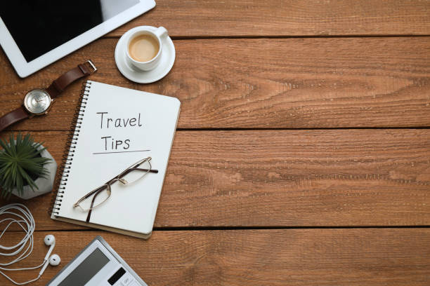 istock Notebook with phrase Travel Tips, cup of coffee and tablet on wooden table, flat lay. Space for text 1446050437
