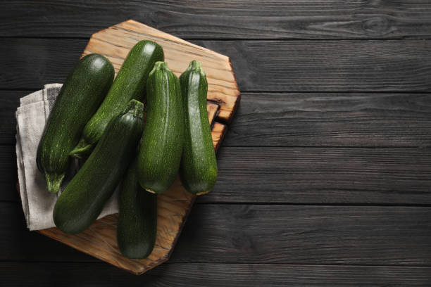 istock Raw ripe zucchinis on black wooden table, top view. Space for text 1446050694