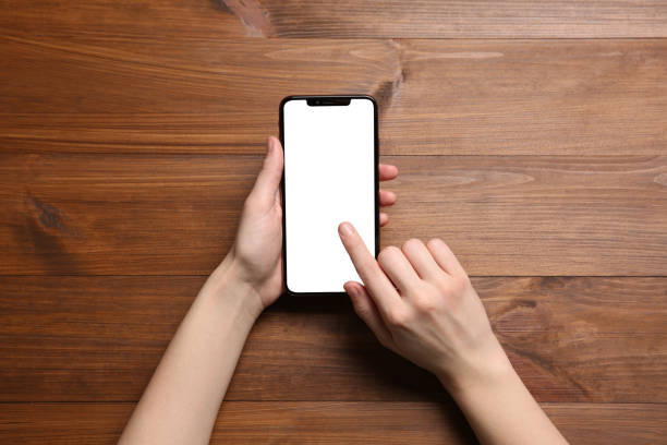 istock Woman using smartphone at wooden table, top view 1446050767