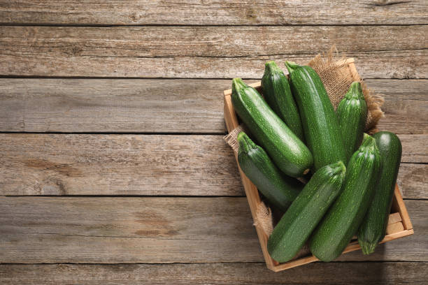 istock Raw ripe zucchinis in crate on wooden table, top view. Space for text 1446051412