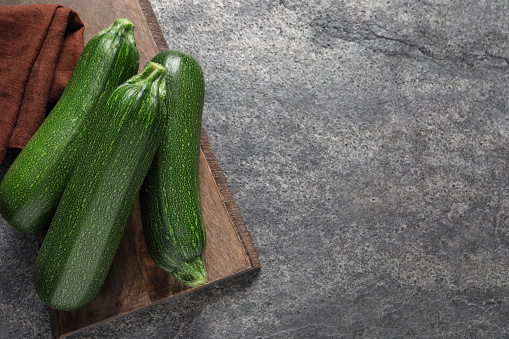 Raw ripe zucchinis on grey table, top view. Space for text