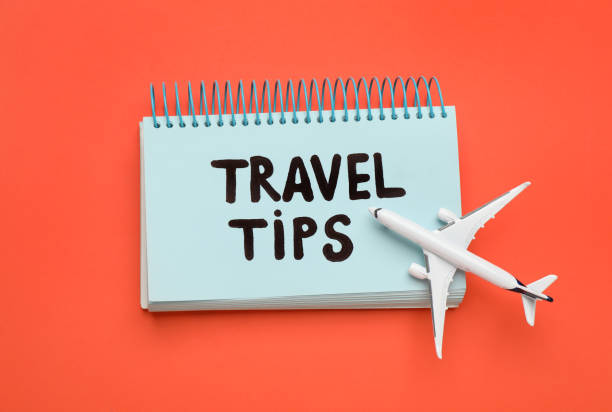 istock Notebook with phrase Travel Tips and toy plane on orange background, top view 1446052420