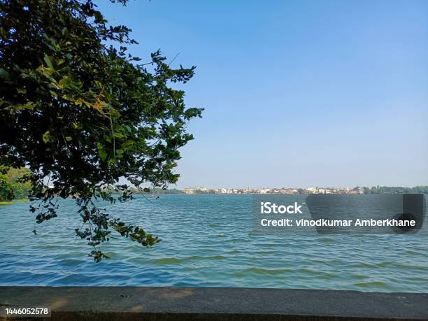 Stock Photo Of Beautiful Rankala Lake Old Stone Retaining Wall Around The Lake Branches Of The Green Tree Overhanging On Water Picture Captured Under Bright Sunny Light At Kolhapur Maharashtra Stock Photo - Download Image Now