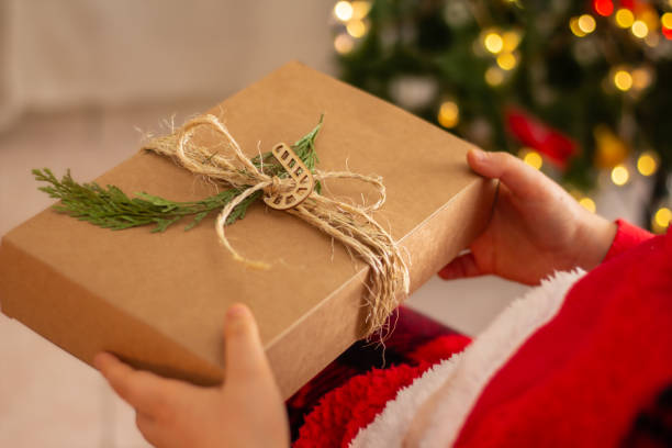 istock Christmas eco-friendly gift wrapping concept, zero waste , environmental protection.Children's hands holding eco-friendly gift wrapping in traditional japanese furoshiki style.Green Christmas 1446053832