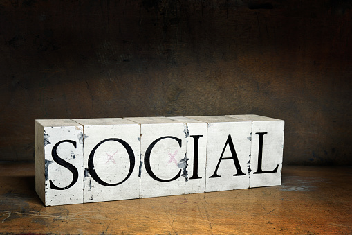 SOCIAL, word with serifs on old and dirty blocks on old wood in dark surroundings. Different words in the same style can be found below: