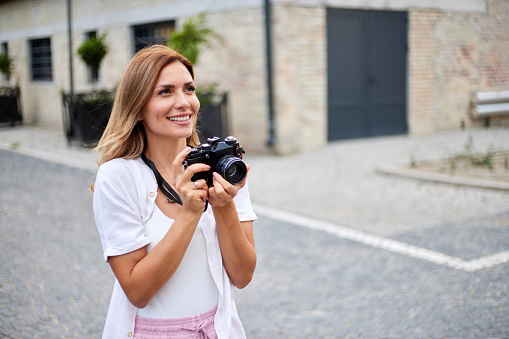 Young woman on city street taking photos with camera