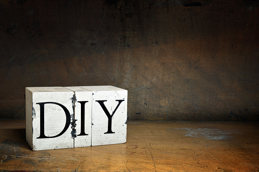 DIY, word with serifs on old and dirty blocks on old wood in dark surroundings. Different words in the same style can be found below: