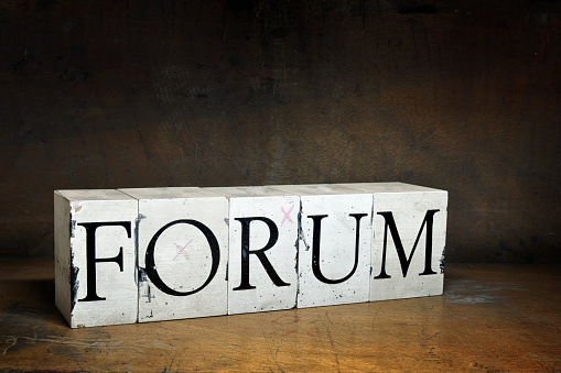 FORUM, word with serifs on old and dirty blocks on old wood in dark surroundings. Different words in the same style can be found below: