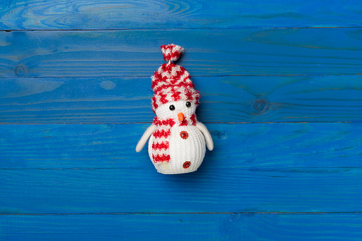 Small Christmas snowman on wooden background, top view.