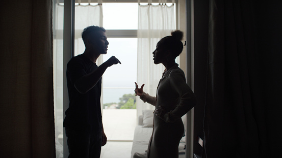 Unhappy african ethnicity couple fighting and gesturing in the living room. Relationship crisis