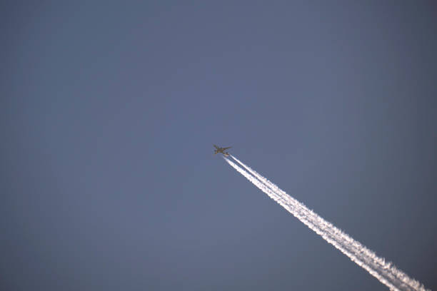 istock Distant passenger jet plane flying on high altitude on clear blue sky leaving white smoke trace of contrail behind. Air transportation concept 1446061527